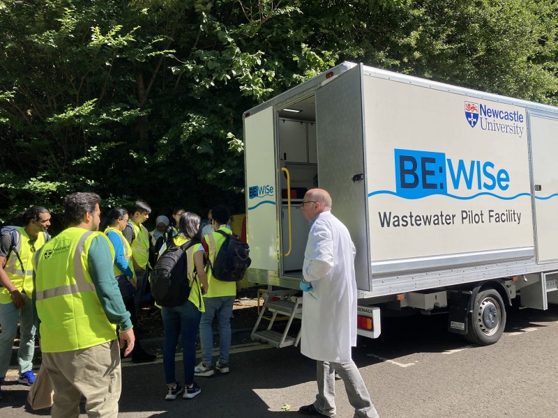 Hub workshop participants explore the lab in a van. Text on the side of the van reads 'BE:WISe, Wastewater Pilot Facility'